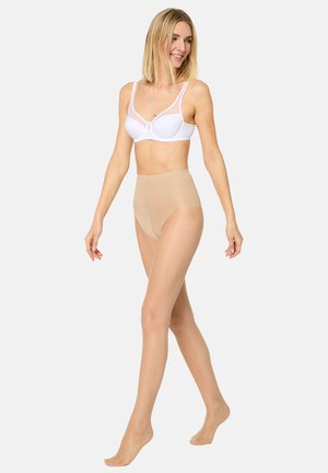 Mallas beige de cintura alta combinadas con un sujetador blanco, con secciones transparentes y textura suave. Las mallas tienen un borde festoneado.