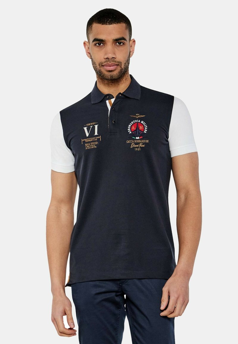 Polo shirt navy e bianco con maniche corte, caratterizzato da loghi ricamati e stampati, colletto e dettagli dorati. Materiale in cotone.