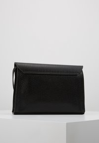 Borsa clutch in pelle nera con finitura texture, caratterizzata da una chiusura a patta e una forma rettangolare strutturata. Nessun dettaglio hardware visibile.