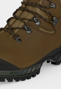 Καφέ δερμάτινο ορειβατικό μποτάκι με μαύρη προστατευτική σόλα, μεταλλικά γάντζους για τα κορδόνια και επενδυμένη γλώσσα για υποστήριξη του αστραγάλου.