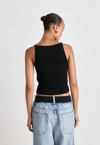 Must muströödiga must cropped tank top õhukeste rihmadega, tekstuurne kangas, koos helesiniste kõrge vöökohaga teksadega, millel on elastne vöökoht.