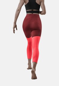 Leggings taille haute, moulants en bordeaux et en corail vif avec des sections en mesh respirant, dotés d'un tissu lisse et d'un design ergonomique.