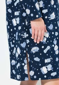 Granatowa sukienka z wesołym białym wzorem przedstawiającym włóczkę, guziki i serca. Boczne rozcięcie i miękka tkanina o luźnym kroju.