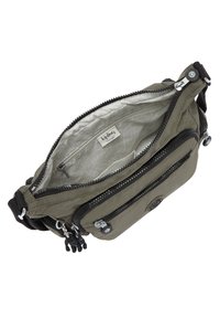Olive green nylon crossbody bag with multiple zippered compartments and a patterned inner lining. Features a round logo and black accents.
