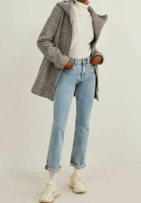 Manteau gris en mélange de laine avec une capuche, col roulé côtelé blanc, jean droit bleu clair et baskets crème avec semelles souples.