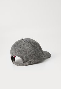 Gray herringbone cap with a curved visor, adjustable strap at the back, and a small logo accent on the strap. Textured fabric.