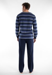 Chemise à rayures bleu marine et bleu clair à manches longues avec un col arrondi, associée à un pantalon de pyjama uni bleu marine.