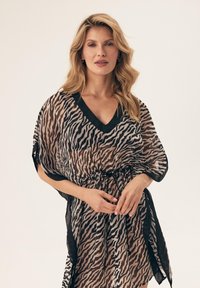 Przezroczysty, czarno-beżowy kaftan w wzór zebra z dekoltem w szpic, opadającymi ramionami i regulowanym paskiem w talii. Lekka, zwiewna tkanina.