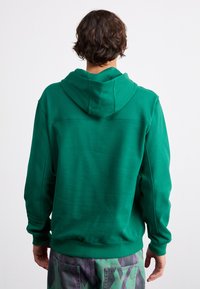 Green hooded sweatshirt with a smooth texture, kangaroo pocket, ribbed cuffs, and hem, showing back view against a plain background.
