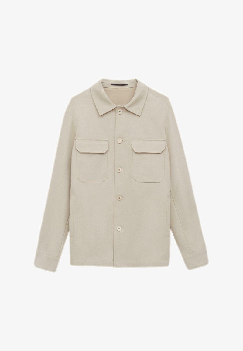 Jasnobeżowa kurtka z teksturowanej tkaniny, z klasycznym kołnierzem, zapięciem na guziki oraz dwiema naszytymi kieszeniami na piersi.