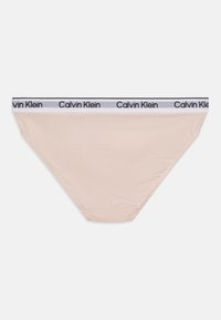 Bézs színű pamut bikini alsónemű fekete-fehér derékszíjjal, amelyen a "Calvin Klein" logó van nyomtatva. Sima textúrájú és normál szabású.