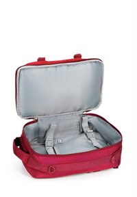 Červená cestovní taška se zipovým otevíráním. Interiér má světle šedou podšívku, dvě nastavitelné popruhy pro upevnění obsahu a minimální vzory.