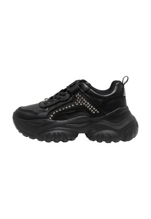 Kraftig svart sneaker med tjock sula, blänkande nitar på sidorna, svarta skosnören och en dragflik på hälen, visas i profil.