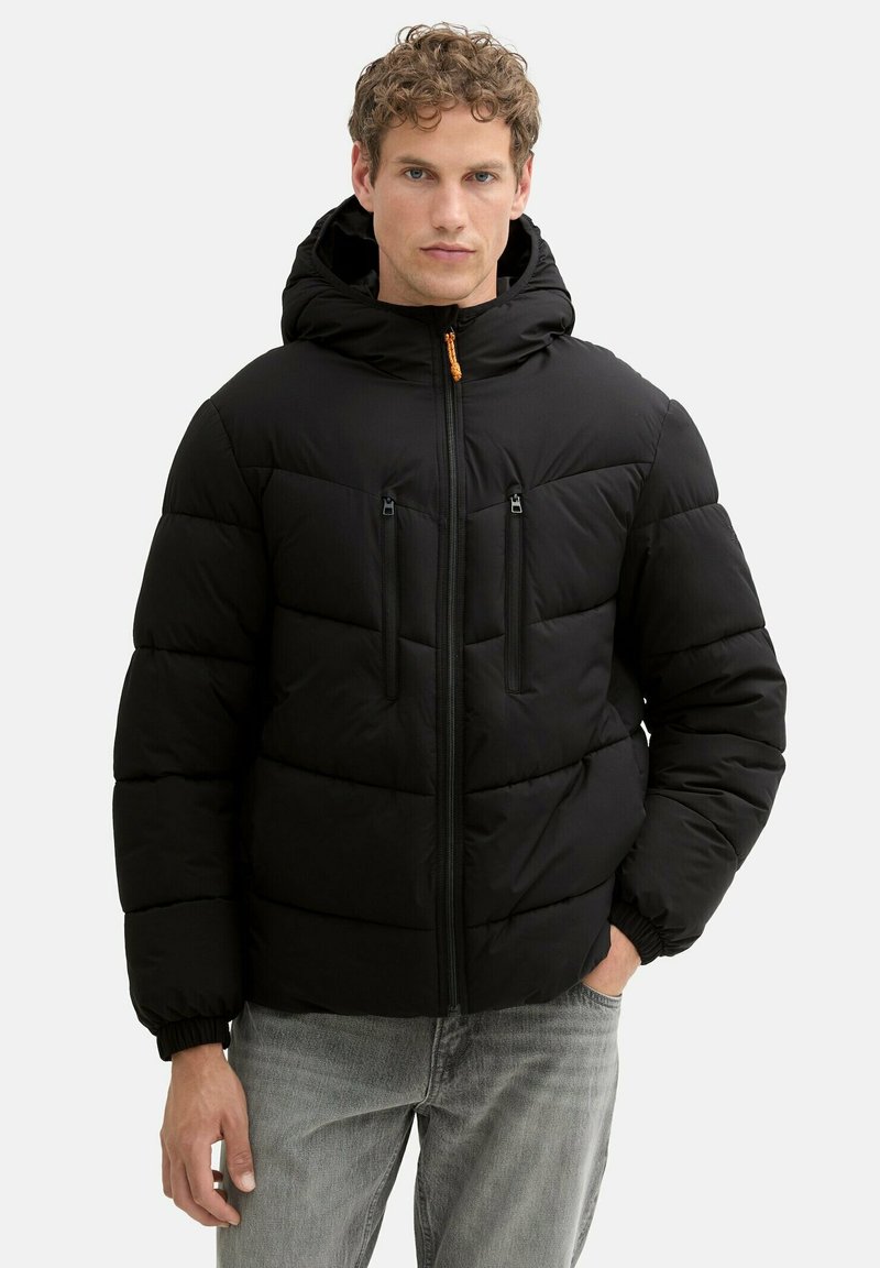 Giubbotto nero imbottito con cappuccio, caratterizzato da cuciture orizzontali, due tasche sul petto con zip e polsini elasticizzati.