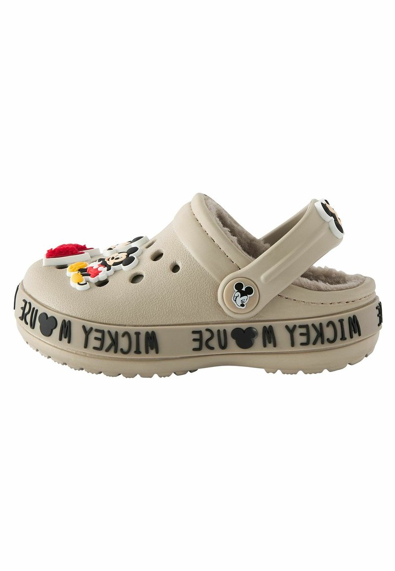 Beige klumpitippa med mjukt inre, prydd med färgglada Mickey Mouse-charms och "Mickey Mouse"-text på bandet; justerbar hälrem.