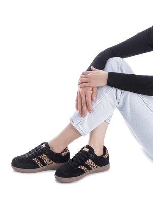 Black suede sneakers featuring leopard print accents, lace-up design, and a textured tan rubber sole. Casual style with contrasting patterns.