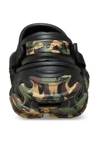 Schwarze und camouflage-musterte Crocs mit einer strukturierten Oberseite, verstellbarem Riemen und einem markanten, konturierten Außensohlen-Design.