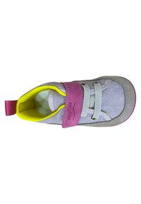 Zapato de tela gris con una correa de velcro rosa, forro amarillo y cordones blancos. Presenta una suela gris y un diseño de punta redondeada.