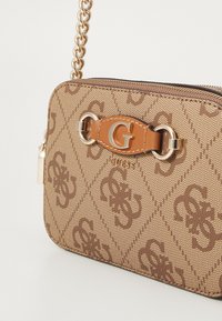 Borsa a tracolla marrone con motivo, dotata di hardware dorato, placca logo centrale e tracolla a catena. Materiale strutturato con un design trapuntato.