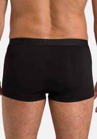 Black cotton boxer briefs with a smooth texture and elastic waistband featuring embossed branding. Fitted design enhances comfort and support.