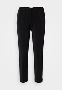Pantalon noir avec une texture lisse, taille élastique et design de jambe fuselée. Présente des poignets aux chevilles et un esthétique minimal.