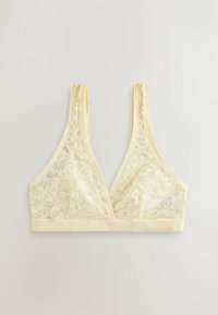 Blød gul blonde-bh med brede stropper, dyb V-udskæring og blomsterprint, lagt fladt på en lys baggrund.