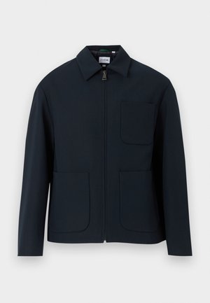 Chaqueta azul marino con cremallera frontal, cuello puntiagudo y dos bolsillos delanteros con bordes redondeados. Confeccionada en una tela suave.