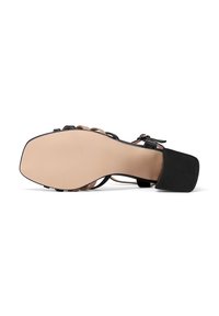 Sandalo con tacco nero, suola beige liscia, design delle cinghie intrigante e tacco in gomma per una migliore aderenza. Presenta una chiusura con fibbia sul lato.