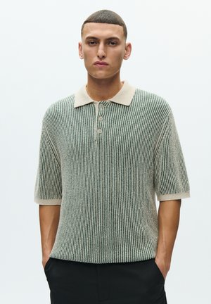 Zöld és krémszínű csíkos kötött galléros póló rövid ujjakkal, gallérral és háromgombos sliccel. Puha textúra, laza szabás.