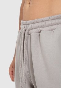 Helle graue Sweatpants mit einem dicken, elastischen Bund, Kordeln und Seitentaschen aus einem weichen, strukturierten Stoff.