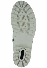 Sole di sneaker bianca con un materiale in gomma testurizzato, motivo a intaglio profondo con forme angolari e un logo circolare sul tallone.