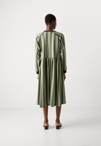 Grün gestreiftes Kleid mit einem gerafften Rock und schwarzen Akzenten an den Ärmeln. Aus glattem Stoff gefertigt, mit einer klassischen A-Linien-Silhouette.