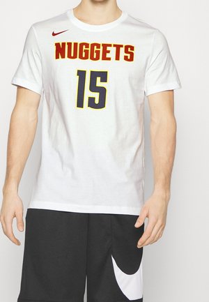 Homme portant un t-shirt blanc des Denver Nuggets avec le numéro 15, et un short de basketball multicolore (rouge, jaune, bleu et noir) avec le logo Nike blanc.