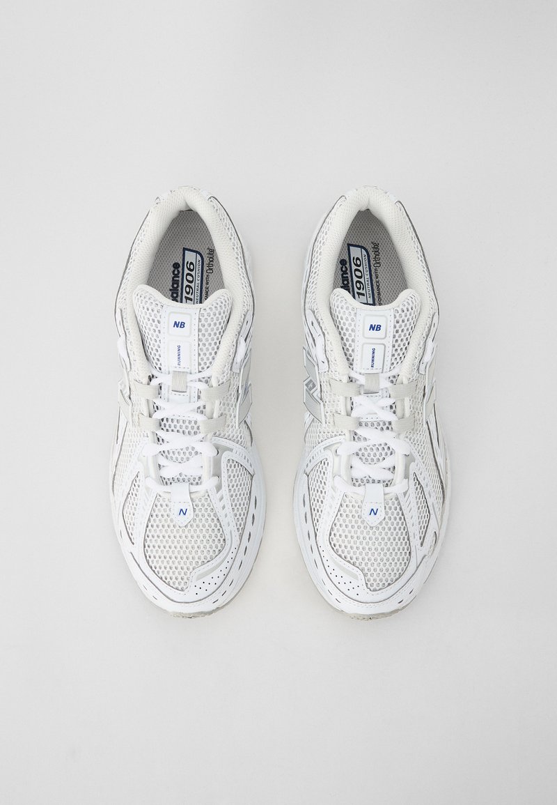 Scarpe da ginnastica bianche in rete con superficie texturizzata, dotate di lacci, logo sulla linguetta e design della suola leggero.