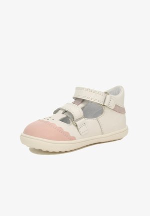 Weiße Lederschuhe mit einer rosa Gummi-Zehenkappe und gewellten Details. Sie verfügen über zwei verstellbare Riemen und Aussparungen zur Belüftung.