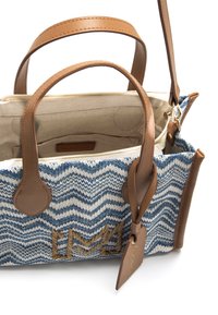 Bolso tejido en azul y blanco con asas y detalles en cuero marrón. Cuenta con cierre de cremallera y un forro interior con etiqueta.