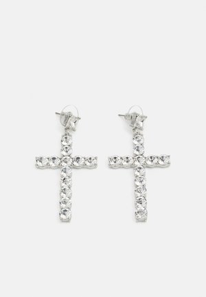 Boucles d'oreilles en croix argentée avec un design en rhinestones clairs, dotées d'un fermoir à clou et d'une surface texturée. Chaque boucle d'oreille est symétrique.
