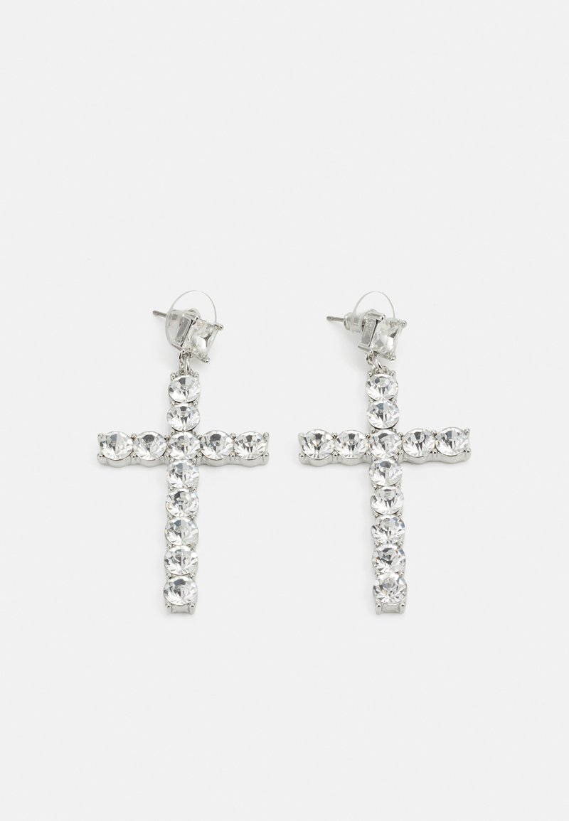Boucles d'oreilles en croix argentée avec un design en rhinestones clairs, dotées d'un fermoir à clou et d'une surface texturée. Chaque boucle d'oreille est symétrique.