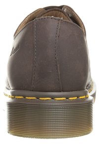 Braune Lederschuhe mit rundem Rücken, gelben Nähten entlang der Sohle und einem strukturierten Gummiabsatz. Flaches Design geeignet für Freizeitschuhwerk.