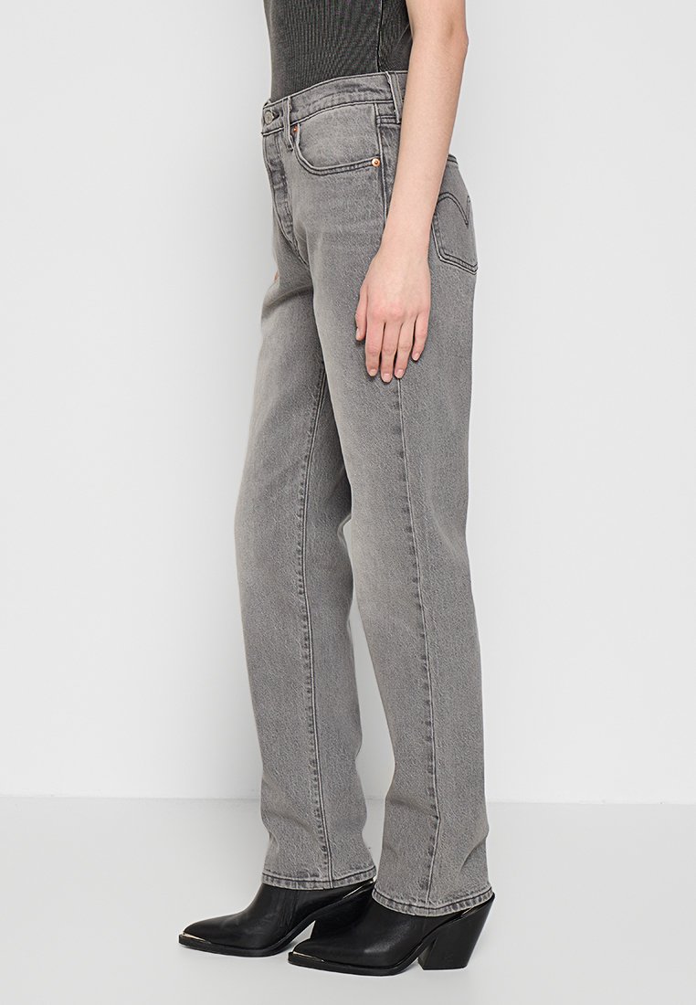 Jeans de mezclilla gris con corte recto, con un diseño clásico de cinco bolsillos y detalles en hardware de cobre. Llevados con botines negros de tacón.