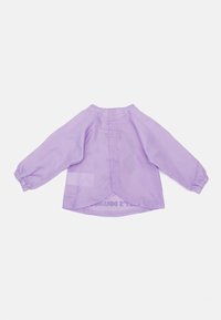 Lavanda srajca z dolgimi rokavi in zaobljenim robom, ima nabrané rokave in osrednji šiv na hrbtni strani. Material izgleda lahkoten in zračnen.