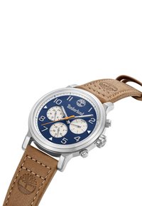 Orologio Timberland con quadrante blu navy, cassa in acciaio inox argentato e cinturino in pelle marrone. Presenta tre sottodial bianchi e un logo posizionato alle 12.