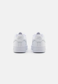 Hvite Nike Air sneakers med glatt lærskinn, polstret krage og teksturert gummisåle. Subtil merkevare på hælen.
