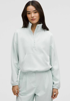 Vaalean mintunvihreä fleece-pullover, jossa on puoliveto-kaulus, etutasku ja elastiset hihansuut. Ominaisuuksiin kuuluvat rento malli ja pehmeä kuitu.