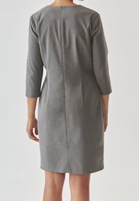 Grå knälång klänning med trekvartslånga ärmar, med en enkel rund halsringning och en dragkedja i mitten bak. Tyget har en subtil textur.