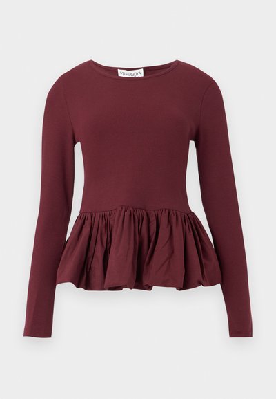 Bluză burgund cu mâneci lungi, cu un corsaj strâmt și tiv cu volane strânse. Materialul pare neted, cu un ușor luciu. Design cu gât rotund.