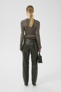 Top metalic maro cu mânecă lungă și pantaloni din piele verzi închis cu talie înaltă. Modelul ține o geantă neagră. Textură netedă și design ajustat.