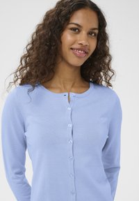 Világoskék kardigán puha anyagból, kerek nyakkivágással, hosszú ujjakkal és hat gombbal az elején.