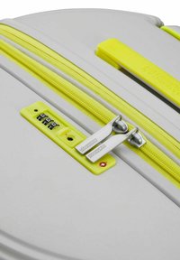 Valise à coque dure grise avec fermeture éclair et accents jaunes vifs. Équipée d'un verrou à combinaison et de tirettes à double fermeture éclair pour plus de sécurité.