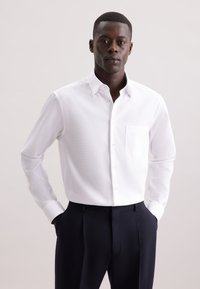 Witte lange mouwen blouse met een gestructureerde stof, enkele borstzak en een klassieke kraag, gecombineerd met marineblauwe geklede broek.
